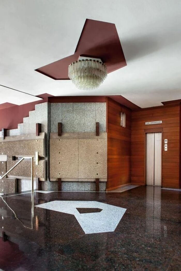 A grand entrance hall with a chandelier and a geometric floor pattern, exemplifying remarkable designs and historic interiors.