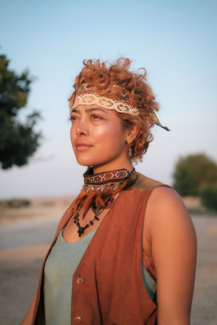 A woman with curly hair and traditional attire, looking into the distance, representing the human side of the Strait of Hormuz.