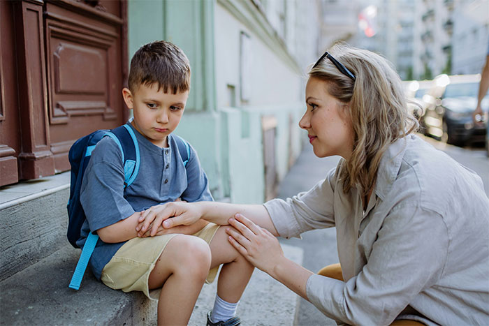 A sympathetic moment after xenophobic remarks, with a child and adult, reflecting defeat and comfort. A sympathetic moment after xenophobic remarks, with a child and adult, reflecting defeat and comfort.