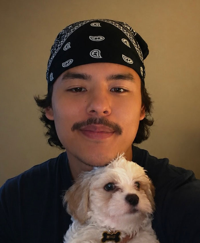 Collin Gosselin wearing a bandana and holding a small white puppy, with a warm expression.