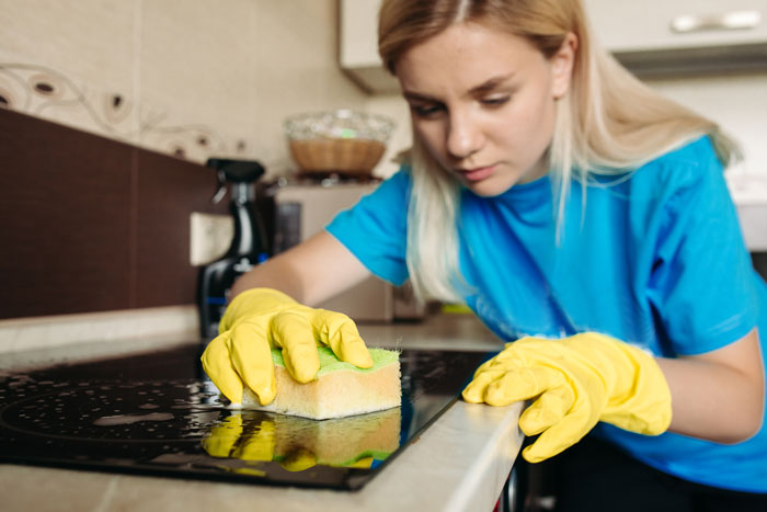 A 27YO woman cleaning a stove, illustrating the toil of hosting a Mom's B-Day. A 27YO woman cleaning a stove, illustrating the toil of hosting a Mom's B-Day.