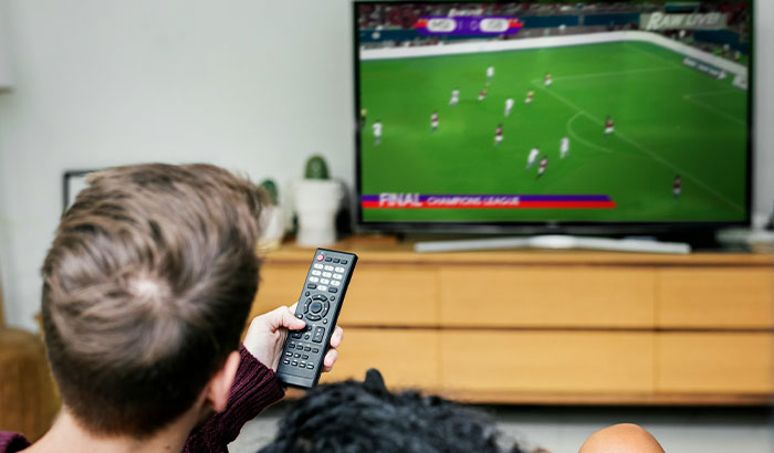 A man watching football on TV, holding a remote control, reflecting his upset about football. A man watching football on TV, holding a remote control, reflecting his upset about football.