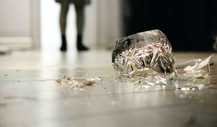 A broken glass on the floor, reflecting a woman's legs in the background, showing the fiancé's response. A broken glass on the floor, reflecting a woman's legs in the background, showing the fiancé's response.