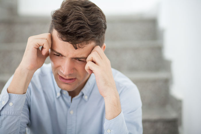 A man with hands on his head, looking distressed, conveying the emotional struggles of men who walked out after having a baby.
