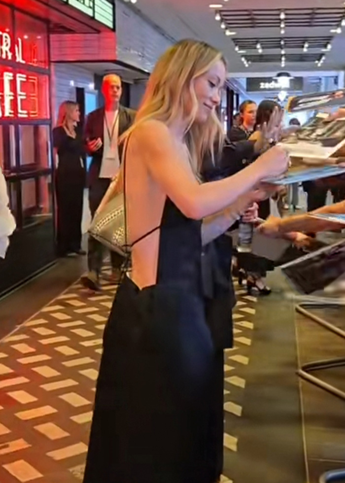 Olivia Wilde's dramatically slimmer frame while signing autographs, showing her back in a black open-back dress. Olivia Wilde's dramatically slimmer frame while signing autographs, showing her back in a black open-back dress.