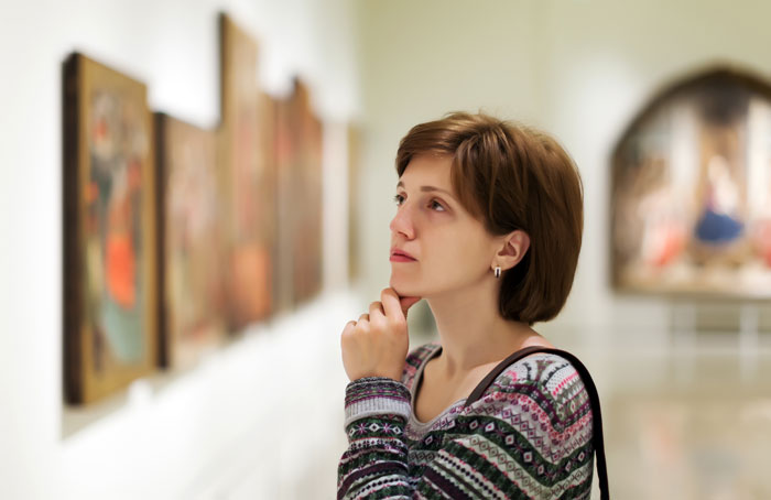 A woman views art in a museum, highlighting cultural experiences that are surprisingly affordable.