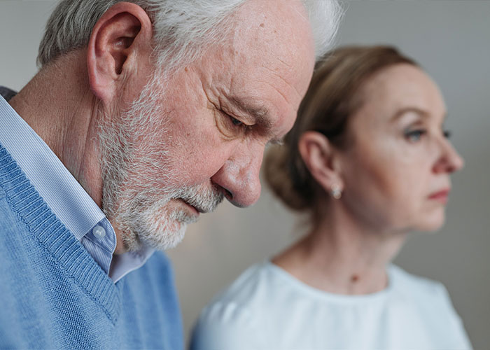 An older man with a pensive expression, representing concerns about dementia symptoms, with a woman in the background. An older man with a pensive expression, representing concerns about dementia symptoms, with a woman in the background.