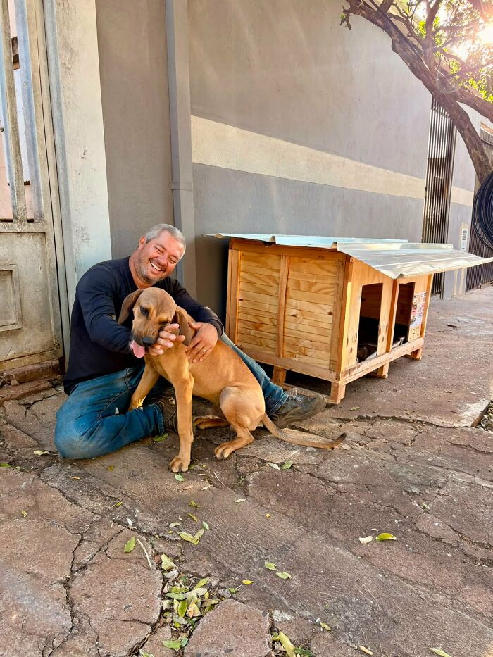 A happy truck driver from Brazil smiles while cuddling a dog next to one of his shelters for animals. A happy truck driver from Brazil smiles while cuddling a dog next to one of his shelters for animals.