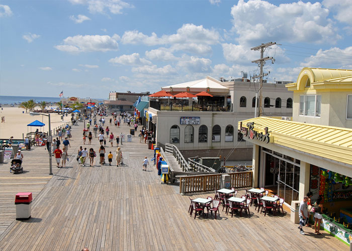 Daytime view of the busy Jersey Shore boardwalk with shops and restaurants.