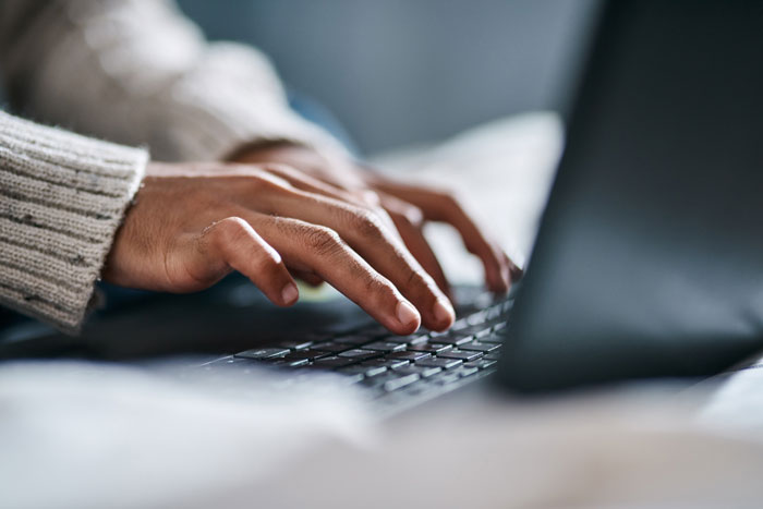 Hands typing on a laptop, perhaps researching how to quit job or sharing infuriating boss stories.