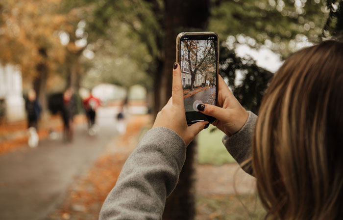 A person holding a phone, taking a picture, sharing hard truths that women learned.