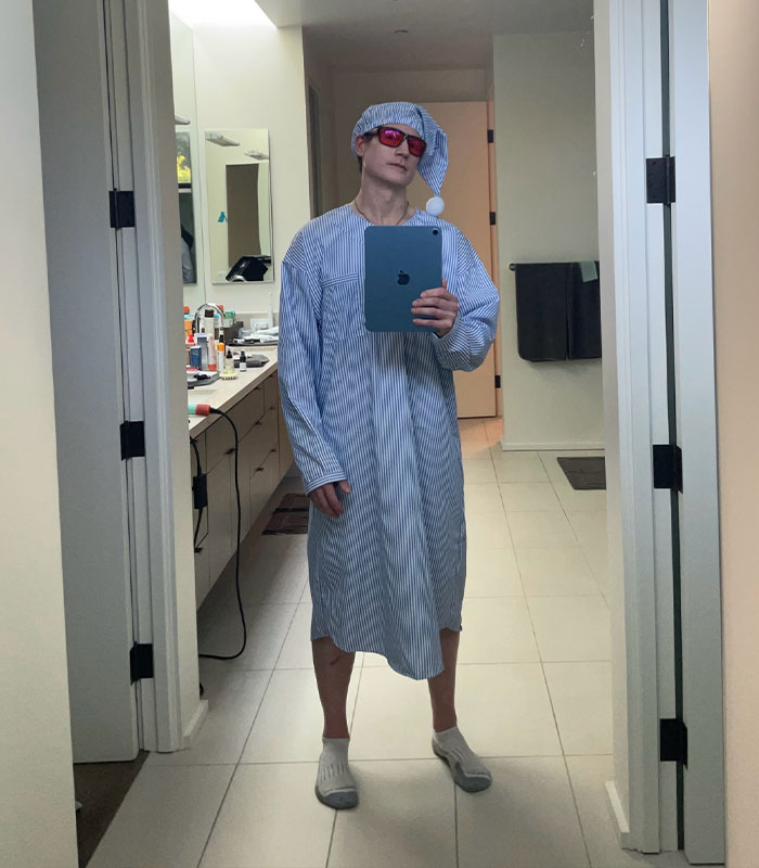 Bryan Johnson in a full-length mirror, dressed in a nightshirt and cap, highlighting his unique lifestyle as a biohacker. Bryan Johnson in a full-length mirror, dressed in a nightshirt and cap, highlighting his unique lifestyle as a biohacker.