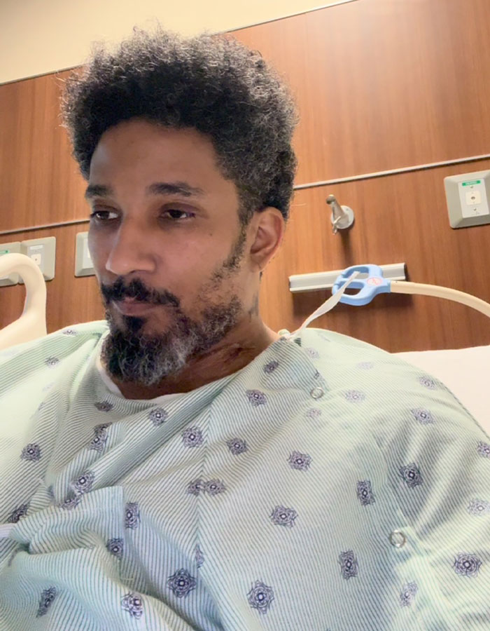 Man in a hospital gown, looking down, in a dire medical situation and needing a transplant because of plants.