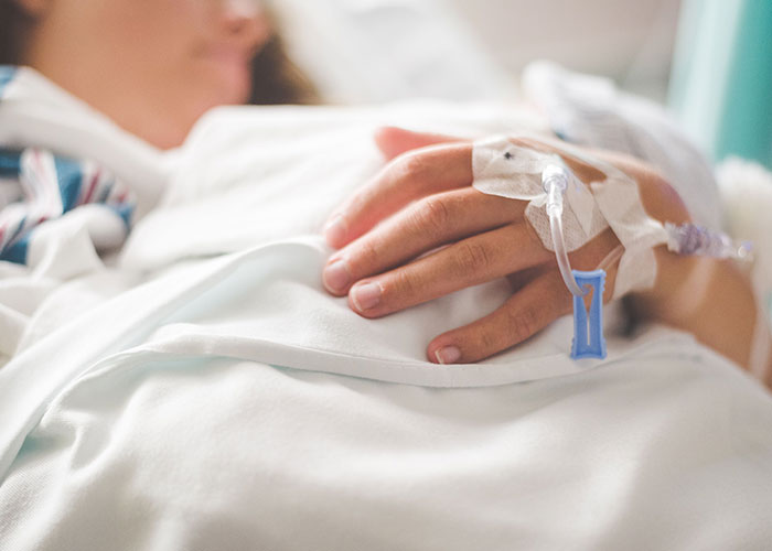 A person in a hospital bed with an IV, showing the loneliest time of life and not looking forward to birthdays.