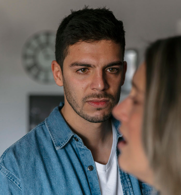 A serious man in a denim shirt looking intently at a woman, depicting hard truths women learned.
