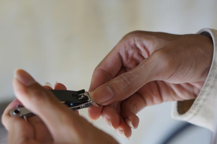 Close-up of a person trimming their nails, highlighting unhygienic practices.