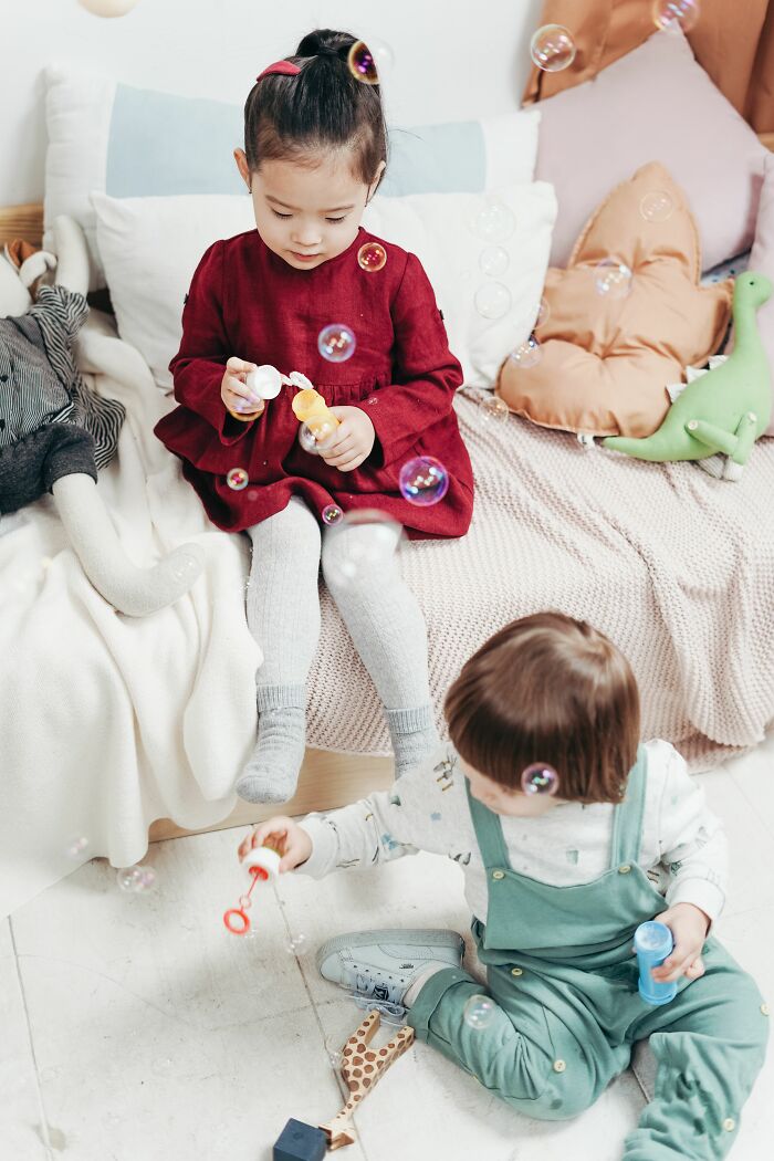 Two young kids playing with bubbles, a moment when kids pretend to understand but are confused by.