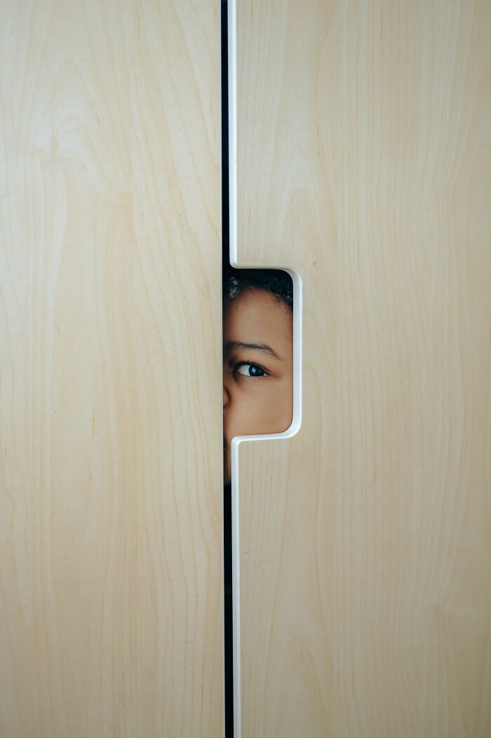 A child's eye peeking through a wooden door, representing things kids pretend to understand but are confused by.