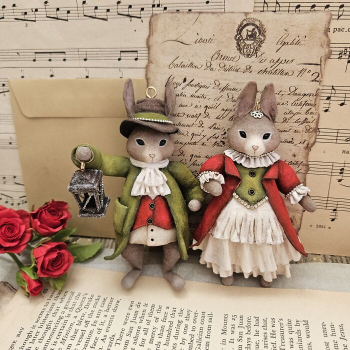 Handmade cotton wool creations: two dressed rabbit figures, vintage style, on old documents.