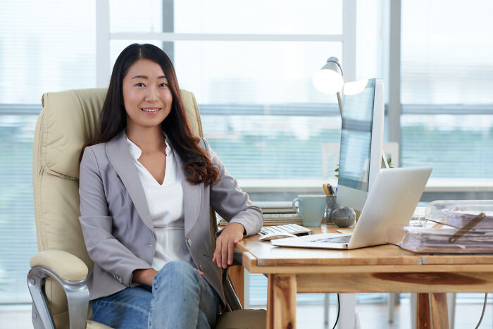 A smiling female worker sitting at her desk, considering corporate buzzwords and practices.