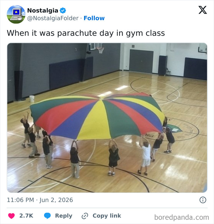 Students in a gym class playing with a colorful parachute, evoking nostalgic memories.