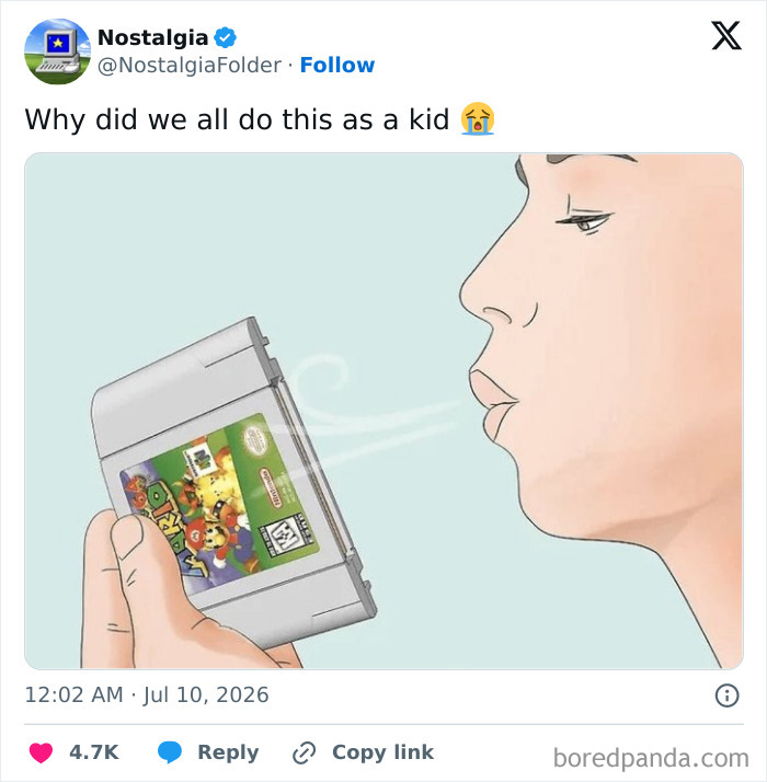 A person blowing on a Nintendo 64 game cartridge, a common act of nostalgia from childhood to fix video games.