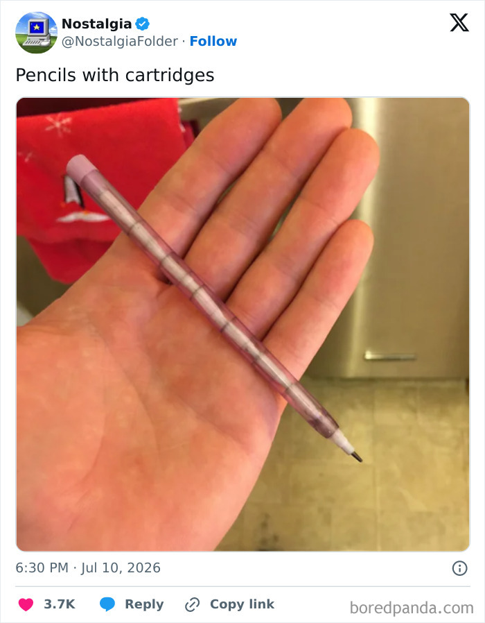 A hand holding a translucent pink mechanical pencil with refillable lead cartridges, evoking a sense of nostalgia.