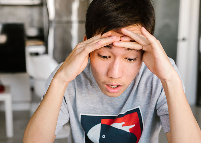 A person with hands on their head, conveying feelings of loneliness and not looking forward to birthdays.