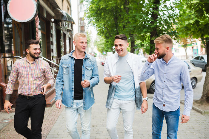 Four men walking down a street, discussing jobs guys have that make women swipe left.