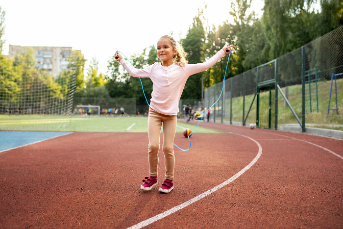 A young girl happily skipping rope outdoors on a track, unrelated to why people got fired.
