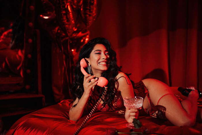A smiling woman on a vintage phone, unaware of potential pocket dial stories, emphasizing the need for lock screens.