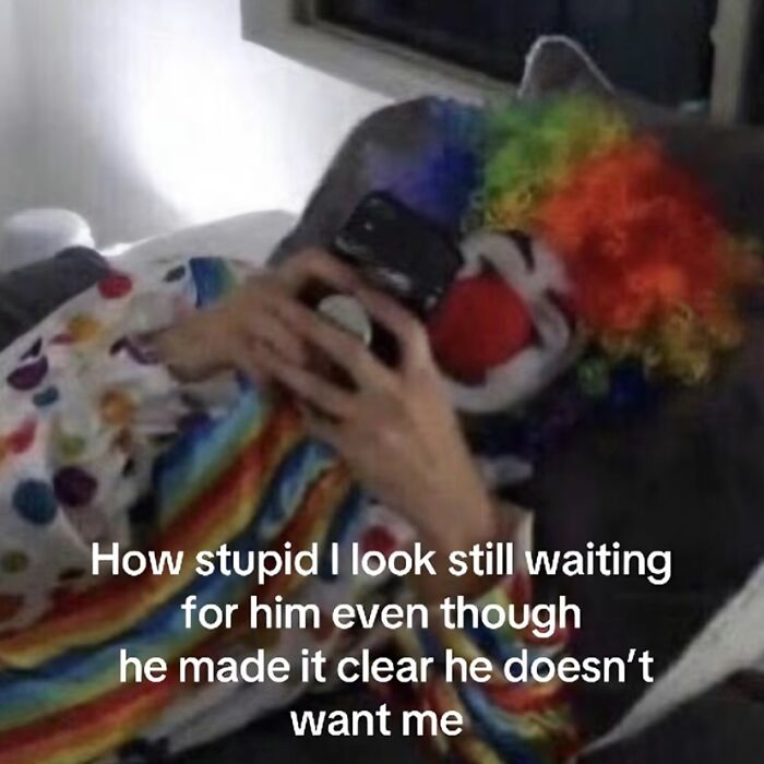 A person dressed as a clown looking at their phone, representing relatable memes.