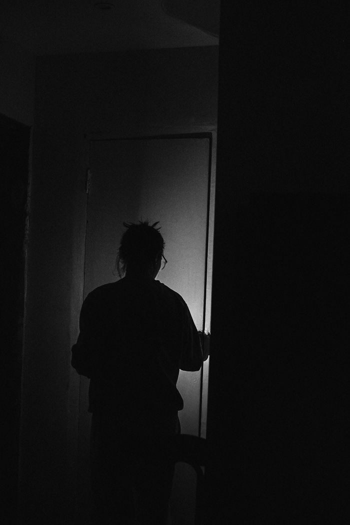 A person's silhouette opening a door in a dark room, evoking a sense of creepy and mysterious things.