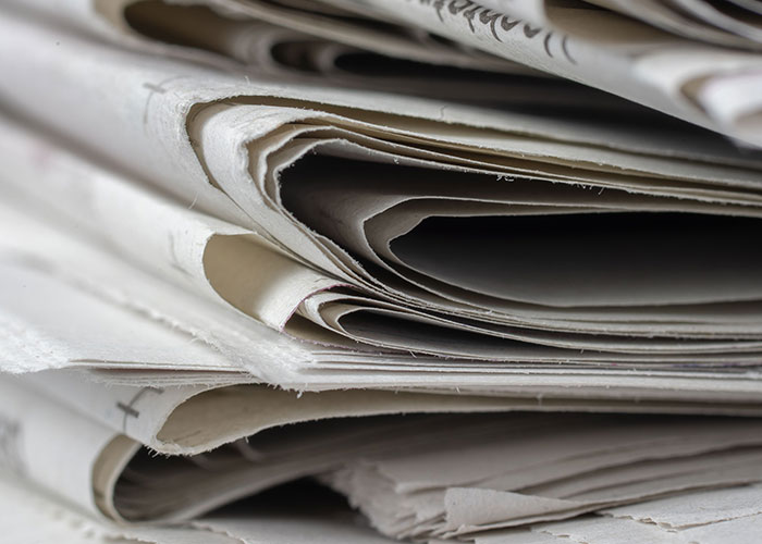 A stack of newspapers, featuring headlines about women's experiences leaving a man's home.