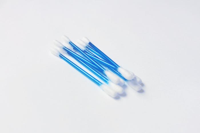 Several blue cotton swabs, potentially used in unhygienic ways, against a white background.
