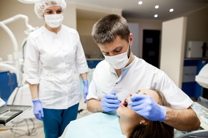 A dentist and assistant treating a patient, highlighting jobs guys have that make women swipe left.