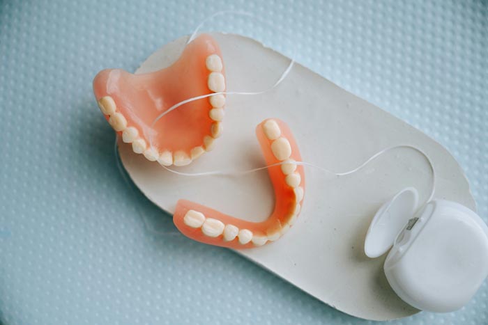 Dentures and dental floss on a white tray, showcasing oral hygiene.