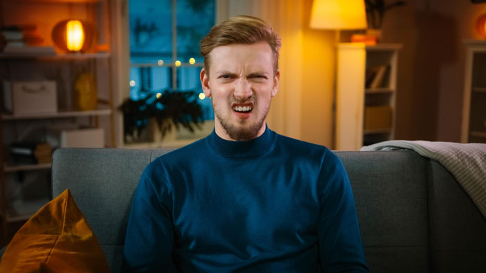 Man refuses to house his mom after learning she secretly harassed his wife over her past trauma, showing a displeased expression.