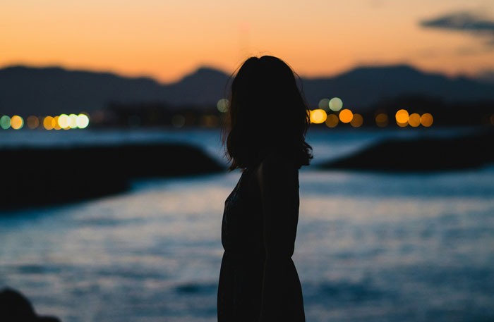 A silhouette of a woman at sunset by the water. Hard truths women learned and shared.