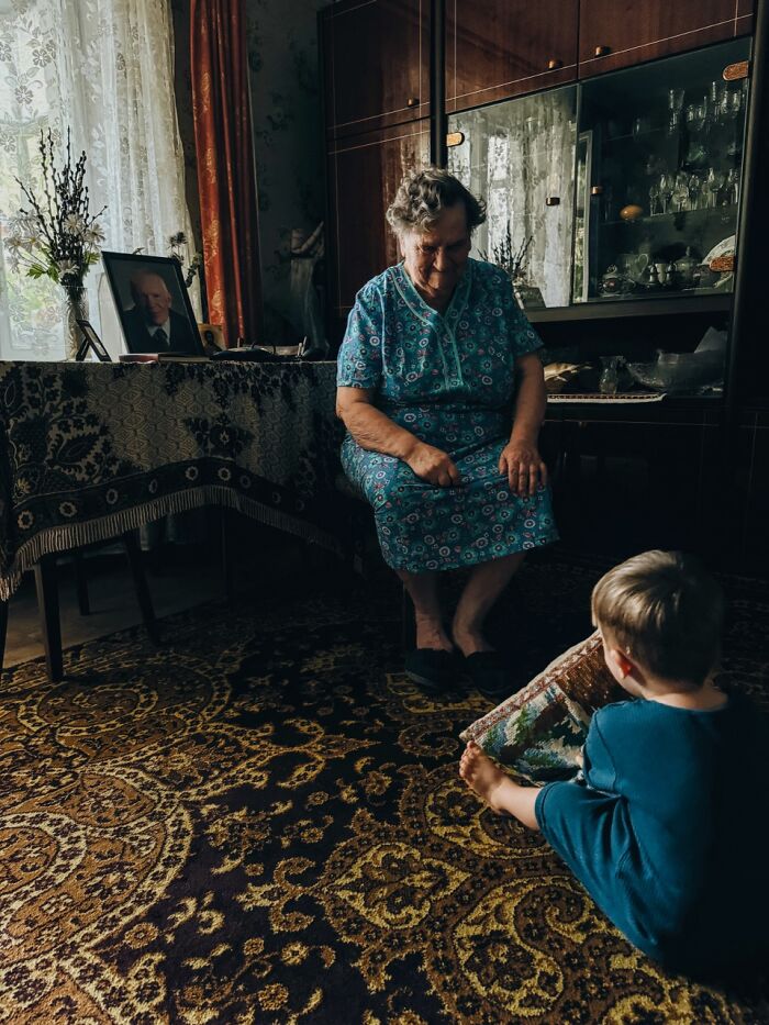 A boy on a patterned rug, looking at an elderly woman sitting in a chair, a winning photo from the iPhone Photography Awards.