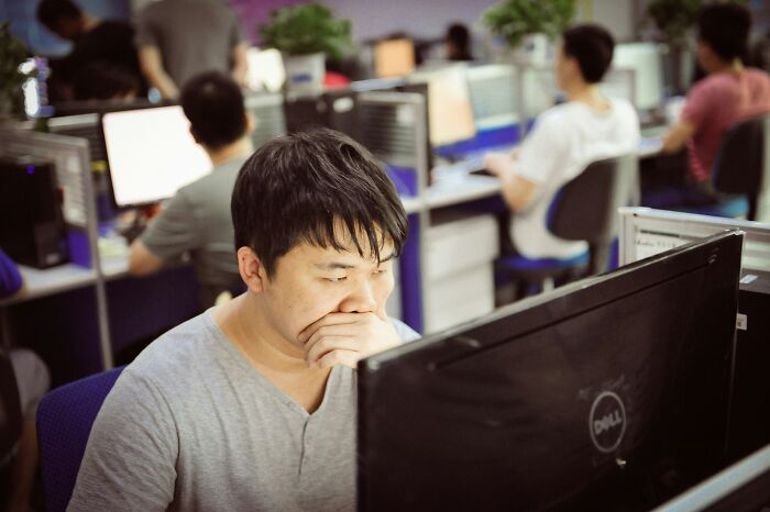 A man looking intently at a computer screen in an office, thinking about reasons why people got fired from their jobs.