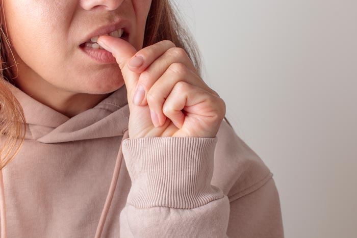 Woman biting her nails, an example of unhygienic personal habits.