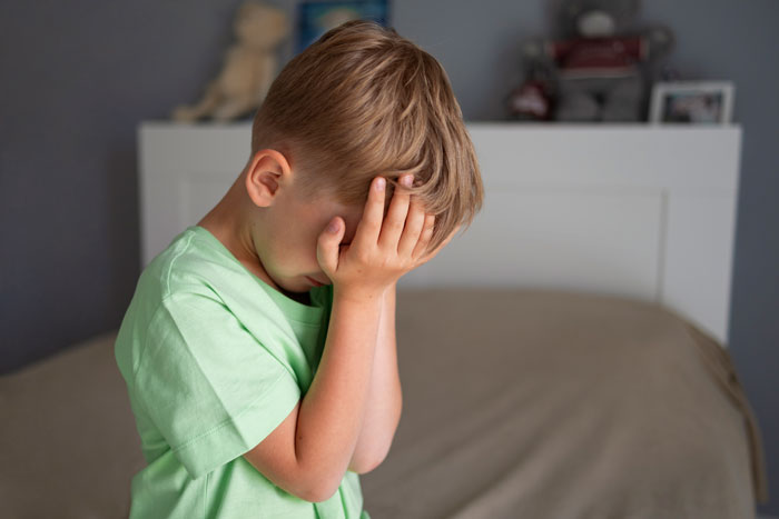 Upset boy, possibly the nephew, covering his face after being punished for punching his baby daughter.