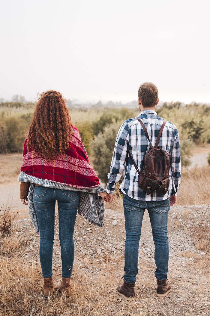 An age-gap couple holding hands and looking at a rural landscape, symbolizing their journey in relationships.