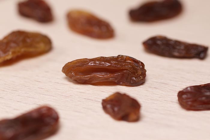 Close-up of raisins on a wooden surface, highlighting unhygienic food handling.