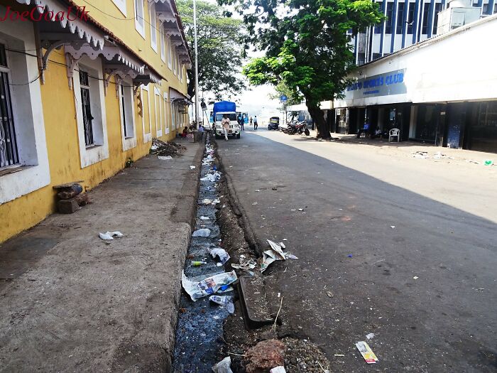 A dirty street with an open sewer filled with trash, illustrating public horror stories in an urban setting.