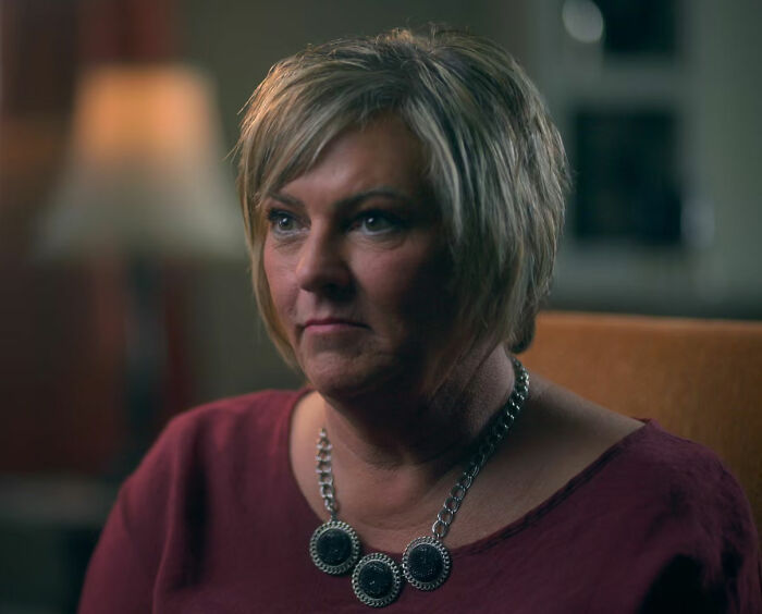 A serious-looking woman, possibly a neighbor, reflecting on the worst neighbor ever and a fatal incident.