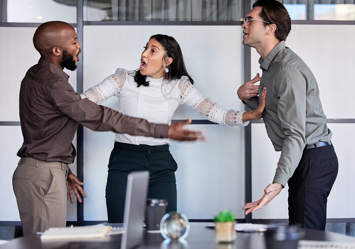 Three coworkers in an office appear to be in a heated argument, illustrating why people got fired from their jobs.