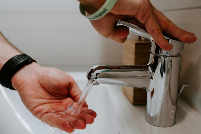 A person washing hands under a faucet, emphasizing hygiene and cleanliness.