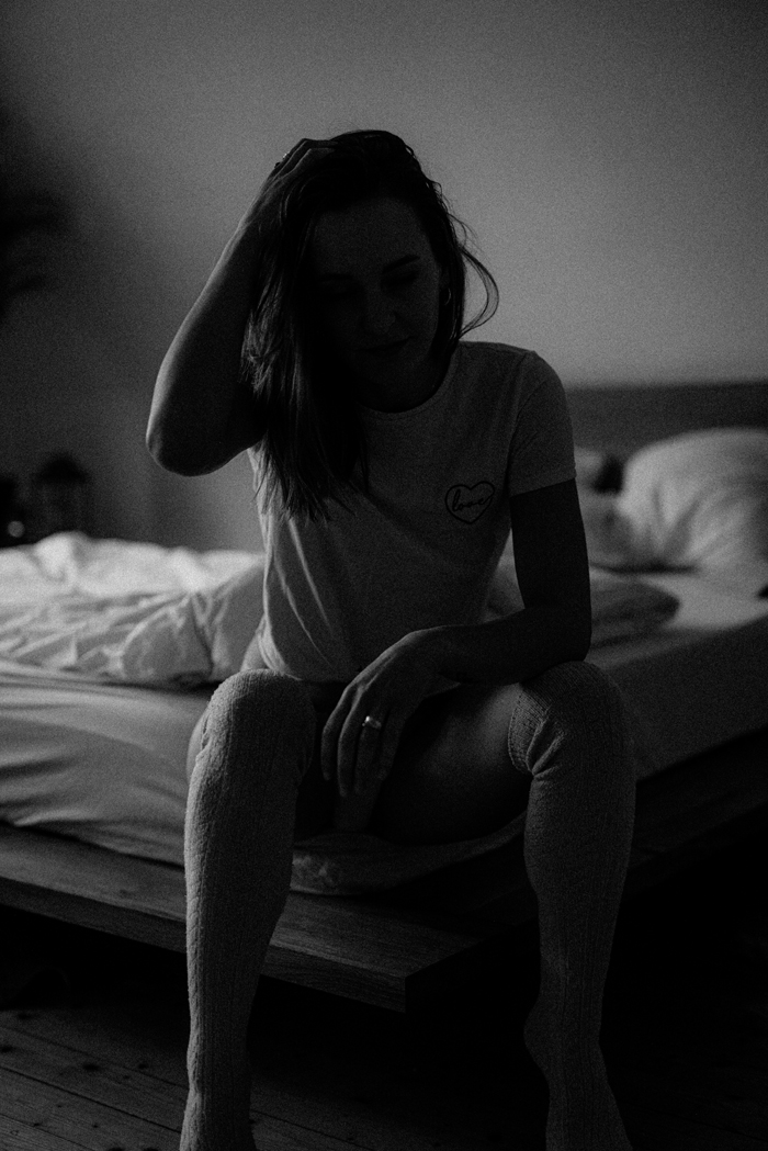 A mysterious, dimly lit image of a woman sitting on a bed, lost in thought, suggesting creepy things happened.